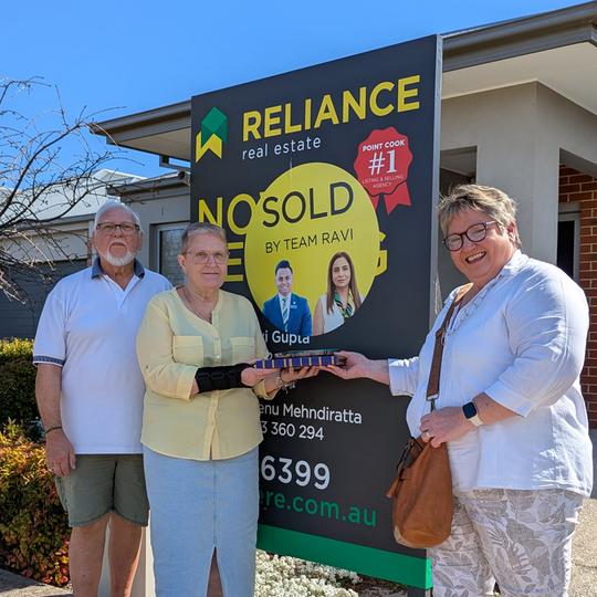 Trish in front of a sold sign outside a house